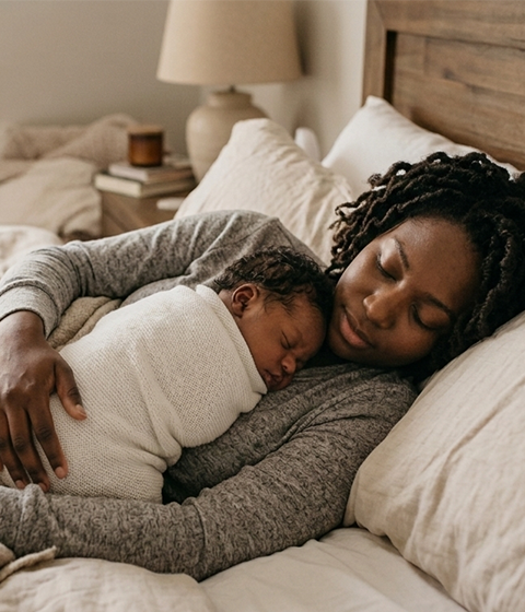 Mother resting comfortably while newborn sleeps beside her